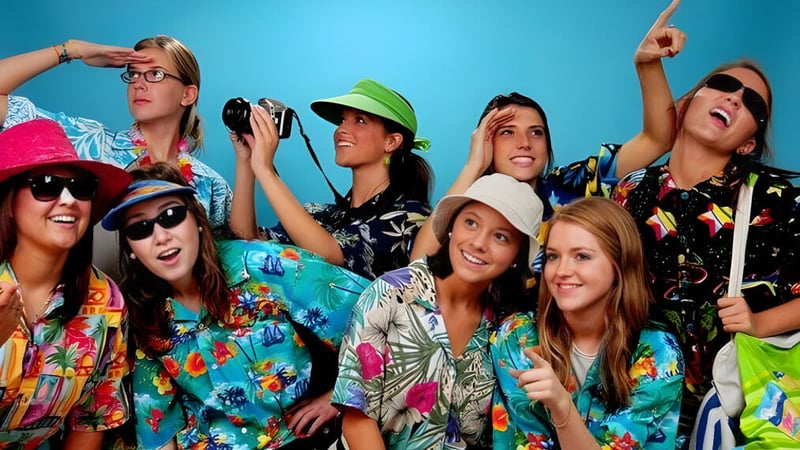 Eine Gruppe junger Frauen posiert mit farbenfroher Kleidung vor blauem Hintergrund auf dem Campus der Aden Bowman Collegiate.