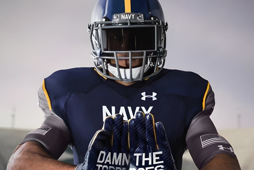 Ein Footballspieler der Admiral Farragut Academy trägt ein Navy-Trikot mit dem Schriftzug „DAMN THE TORPEDOES“ in einer düsteren Umgebung.