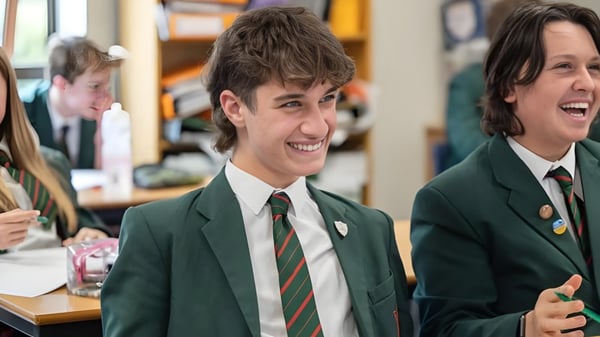 Zwei Schüler der Akeley Wood School unterhalten sich und lachen im Klassenraum mit Schulmaterialien im Hintergrund.