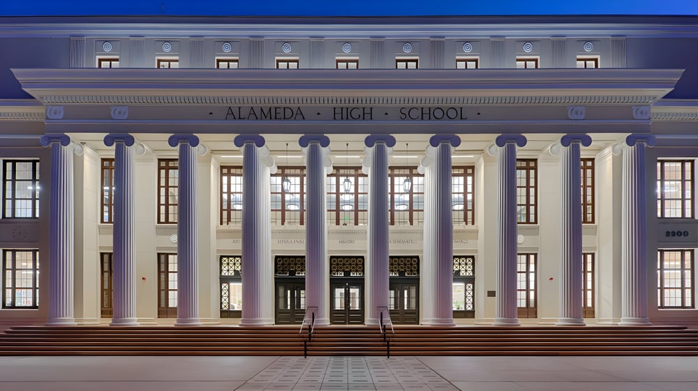 Das neoklassizistische Hauptgebäude der Alameda High School ist nachts beleuchtet zu sehen.