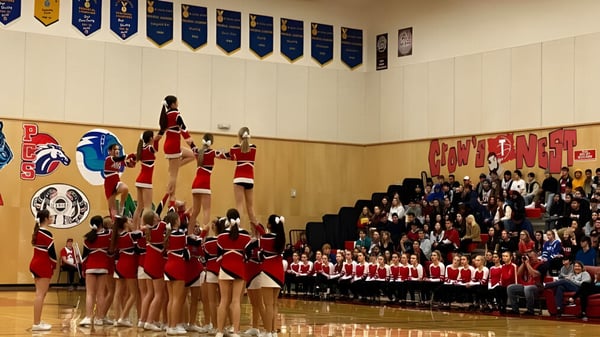 Eine Gruppe Cheerleader führt eine Tanzdarbietung auf der Bühne der Alberni District Secondary School vor Publikum auf.