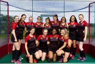 Eine Gruppe junger Athletinnen der Albyn School posiert zusammen auf einem Sportplatz mit Netz im Hintergrund.