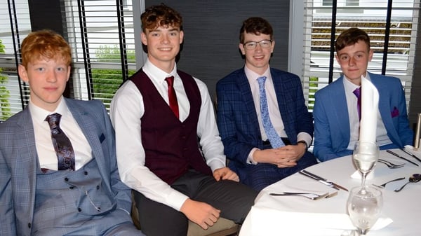 Vier Schüler der Albyn School sitzen in formeller Kleidung an einem Tisch in einem Büro mit Fenster im Hintergrund.