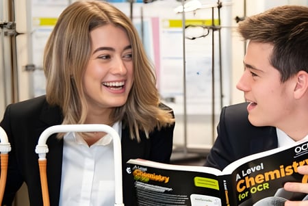 Zwei Schülerinnen und Schüler der Aldenham School unterhalten sich lebhaft bei gehaltenen Lehrbüchern.