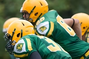 Eine Gruppe von Football-Spielern der Aldershot High School steht in grünen und gelben Trikots auf dem Fußballfeld.