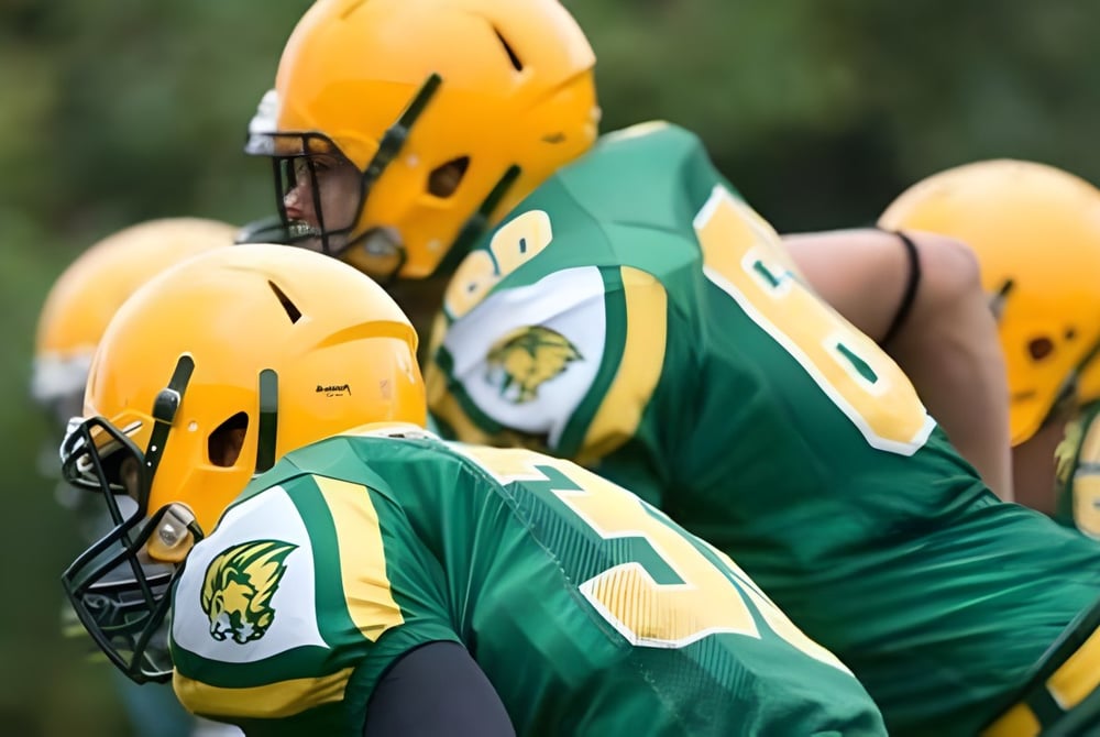 Eine Gruppe von Football-Spielern der Aldershot High School steht in grünen und gelben Trikots auf dem Fußballfeld.