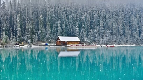 Eine kleine Holzhütte steht am Ufer eines türkisfarbenen Sees vor einem verschneiten Wald auf dem Gelände der Alexander Galt Regional High School.