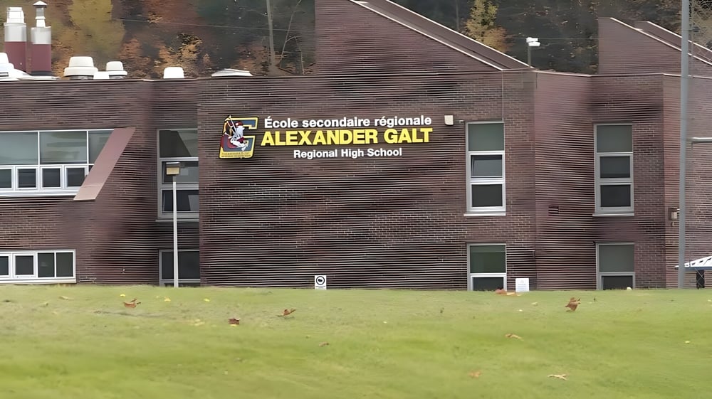 Das große Backsteingebäude der Alexander Galt Regional High School ist von einer Wiese mit herbstlichem Laub umgeben.