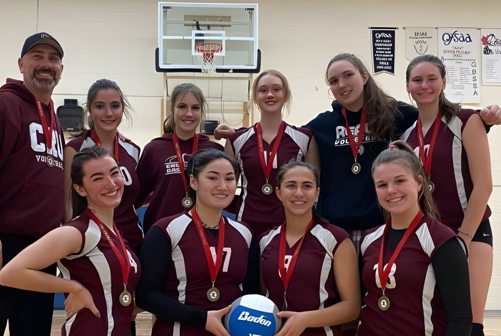 Eine Gruppe junger weiblicher Athletinnen steht in der Sporthalle der Alexander Mackenzie High School vor einem Basketballkorb.