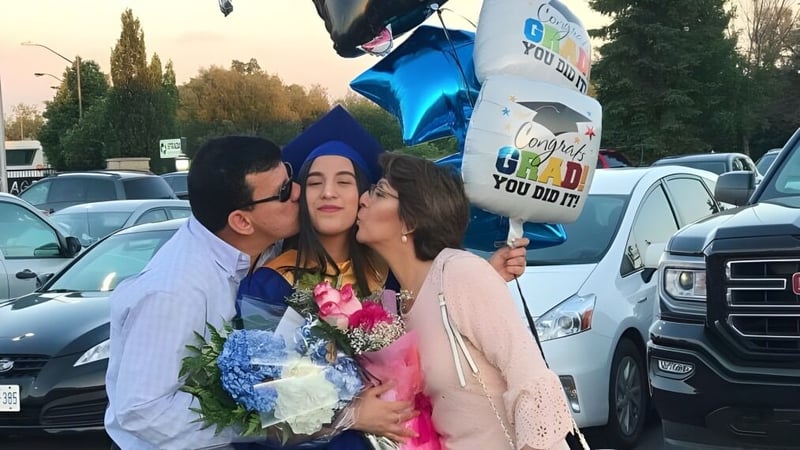 Drei Personen stehen zusammen und lächeln auf dem Parkplatz der Alexander Mackenzie High School.