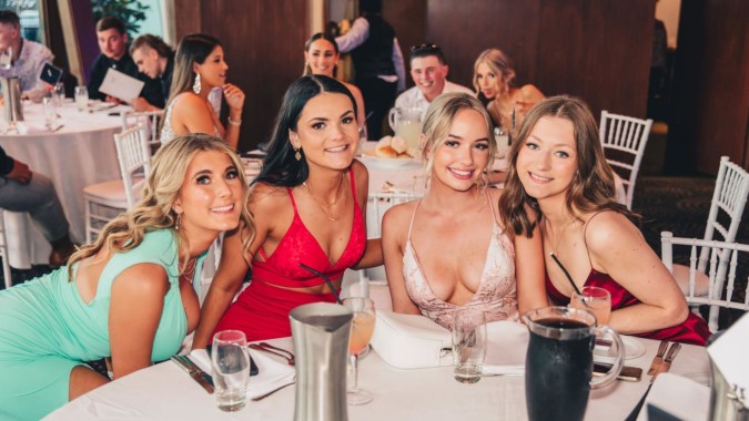 Eine Gruppe Frauen in formeller Kleidung sitzt bei einer Veranstaltung auf dem Campus des Alexandra College.