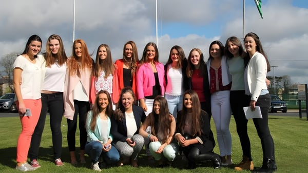 Eine Gruppe Schülerinnen steht auf einer Wiese im Außenbereich des Alexandra College unter bewölktem Himmel.