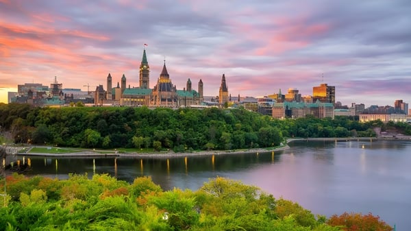 Die Skyline einer Stadt spiegelt sich bei Sonnenuntergang im Fluss vor dem Campus des Algonquin College.