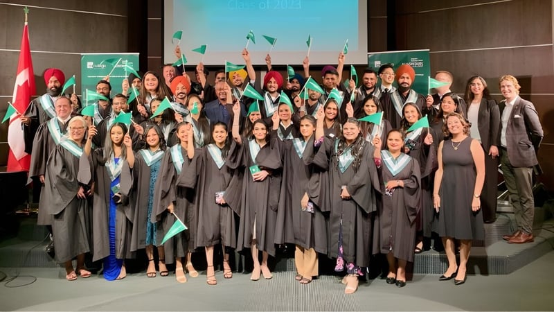 Eine große Gruppe von Absolventinnen und Absolventen steht vor einem Algonquin College Logo in ihren Abschlussroben.