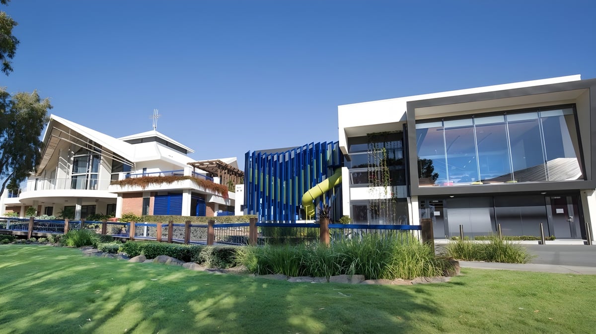 Das moderne mehrstöckige Gebäude der All Saints Anglican School ist von gepflegtem Rasen und Bepflanzung umgeben unter klarem blauem Himmel.