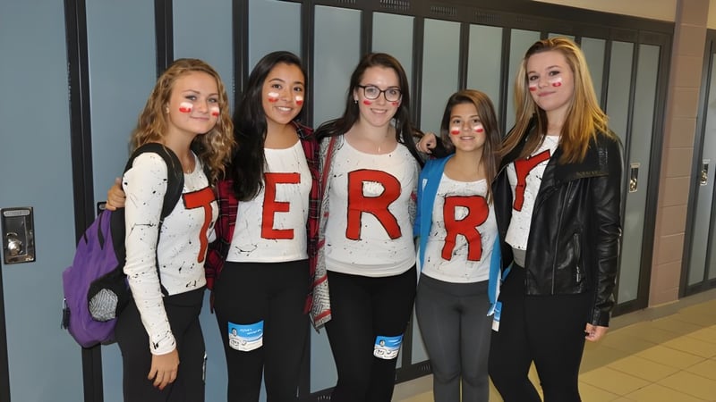 Fünf Schülerinnen der All Saints Catholic Secondary School stehen gemeinsam im Schulgebäude mit identischen TERROR T-Shirts.