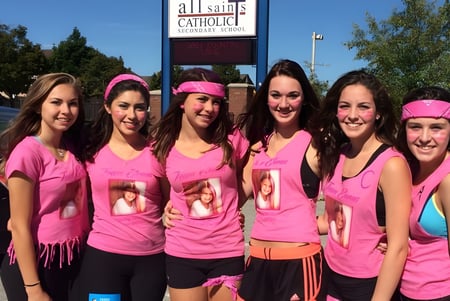 Eine Gruppe Schülerinnen steht vor dem Kirchengebäude der All Saints Catholic Secondary School.