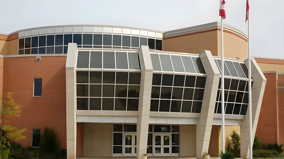 Das moderne mehrstöckige Gebäude mit Glasfassade auf dem Campus der All Saints Catholic Secondary School ist von Bäumen umgeben.