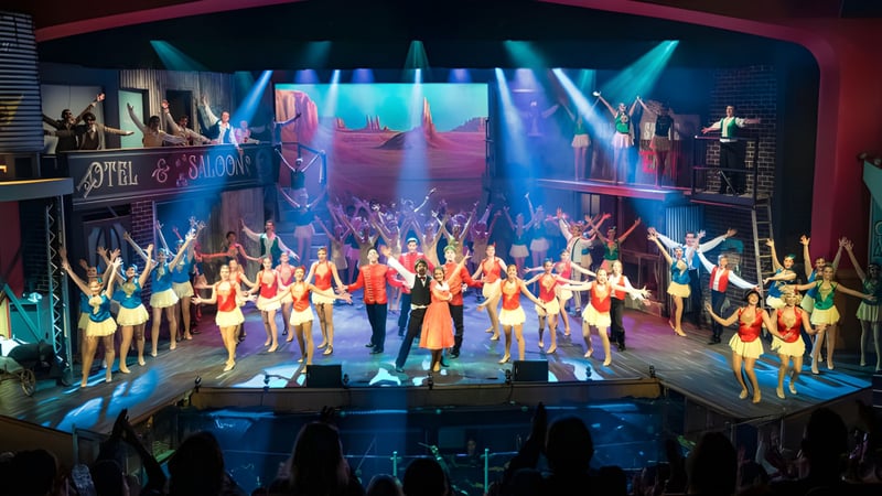 Schüler der All Saints Anglican School führen eine Bühnenperformance mit bunten Kostümen und dynamischer Beleuchtung auf.