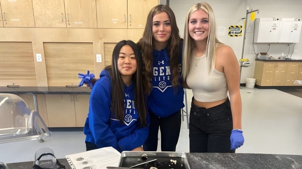 Drei Schülerinnen der All Saints High School in Calgary stehen zusammen und lächeln im Spindraum.