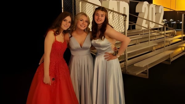 Drei Schülerinnen der All Saints High School Calgary posieren gemeinsam auf einer Tribüne im Freien.