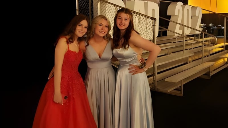 Drei Schülerinnen der All Saints High School Calgary posieren gemeinsam auf einer Tribüne im Freien.