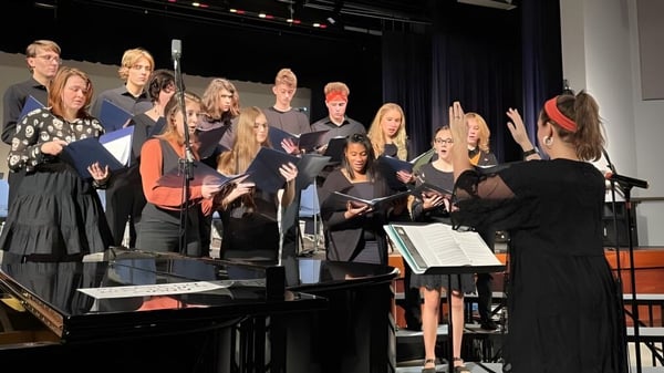 Schüler der Allendale Columbia School treten gemeinsam mit Instrumenten und Noten auf einer Bühne auf.