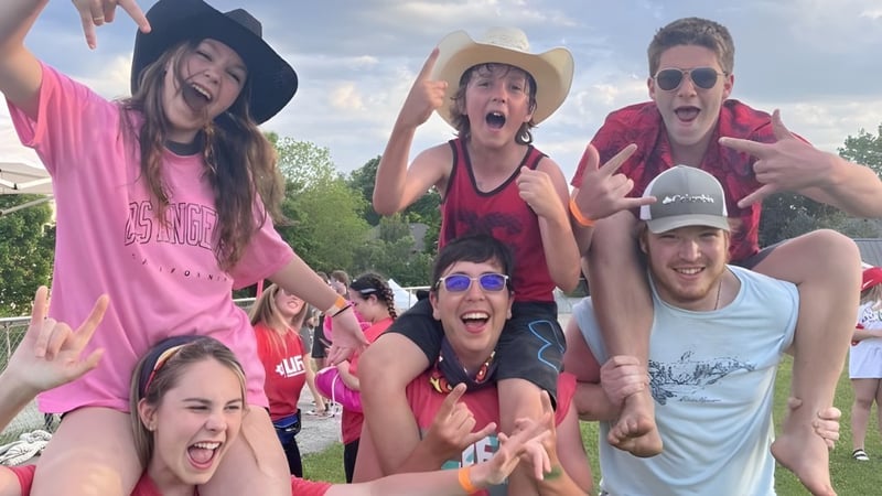 Eine Gruppe von Schülerinnen und Schülern der Almonte & District High School zeigt draußen lebendige Posen vor grüner Kulisse.