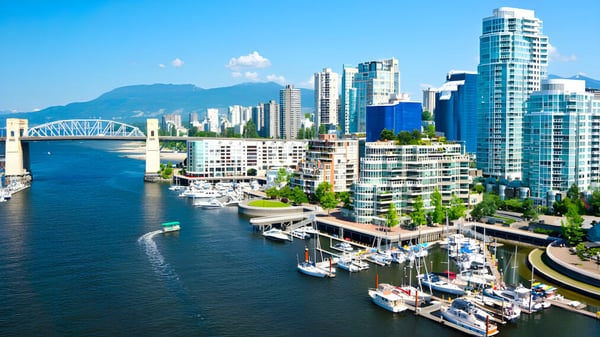 Eine belebte Stadtansicht mit Hochhäusern, Hafen und Brücke bei klarem Himmel, ohne direkten Bezug zur Alpha School.