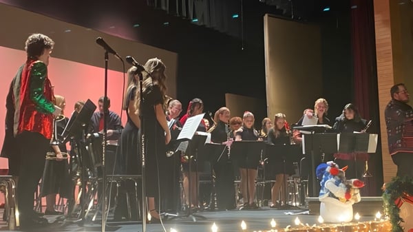 Der Chor und Musiker der American Falls High School treten auf einer Bühne vor einem Publikum in einem abgedunkelten Saal auf.