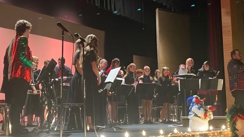 Der Chor und Musiker der American Falls High School treten auf einer Bühne vor einem Publikum in einem abgedunkelten Saal auf.