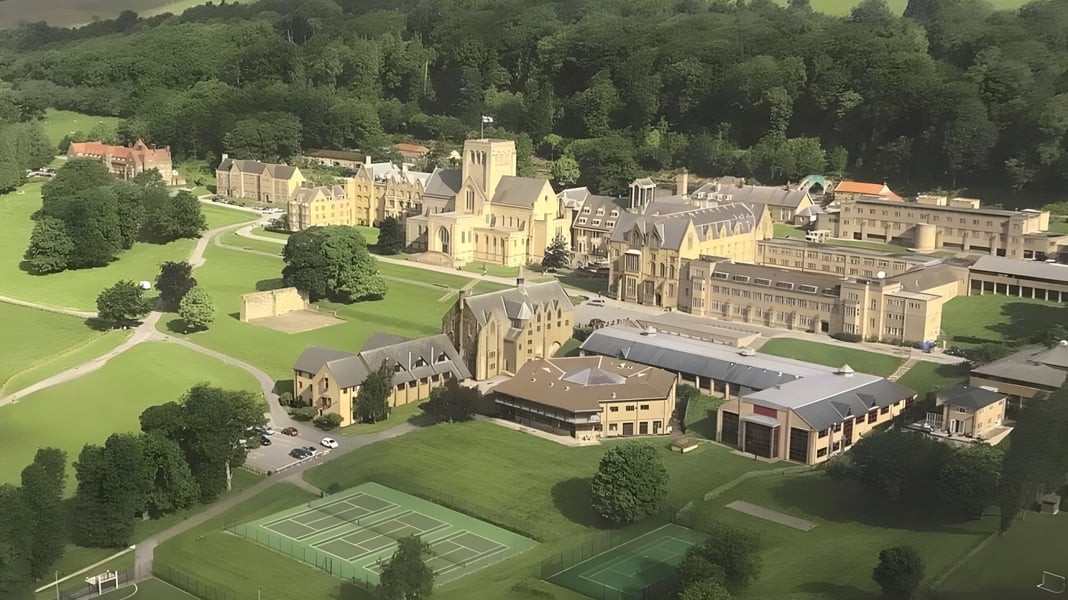 Das Ampleforth College zeigt ein mittelalterliches Schloss mit gepflegten Rasenflächen und Tennisplätzen in einer grünen Landschaft.