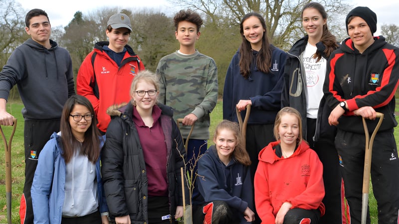 Eine Gruppe Schülerinnen und Schüler des Ampleforth College steht draußen vor Bäumen und Grünfläche.