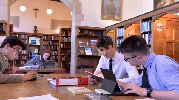 Studierende des Ampleforth College lernen gemeinsam in der Bibliothek umgeben von Bücherregalen und Lernmaterialien.