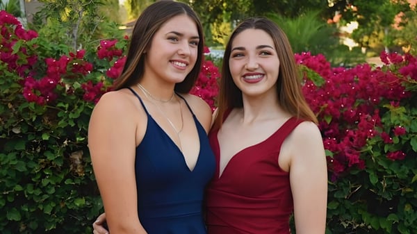 Zwei Schülerinnen vor einem üppigen Garten mit roten Blumen auf dem Gelände der Anaheim Union High School District.