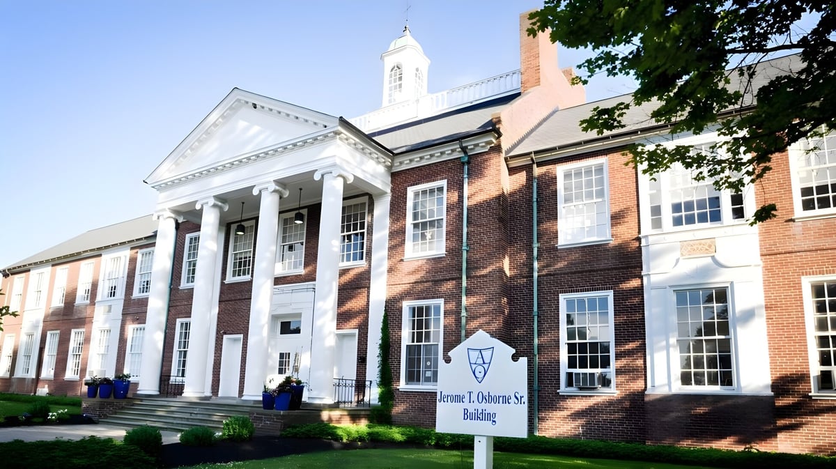 Das Backsteingebäude der Andrews Osborne Academy mit Säulenvorbau und Uhrenturm umgeben von Grünflächen.
