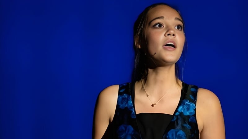 Porträt einer jungen Frau mit dunklen Haaren vor einem blauen Hintergrund auf dem Campus der Andrews Osborne Academy.