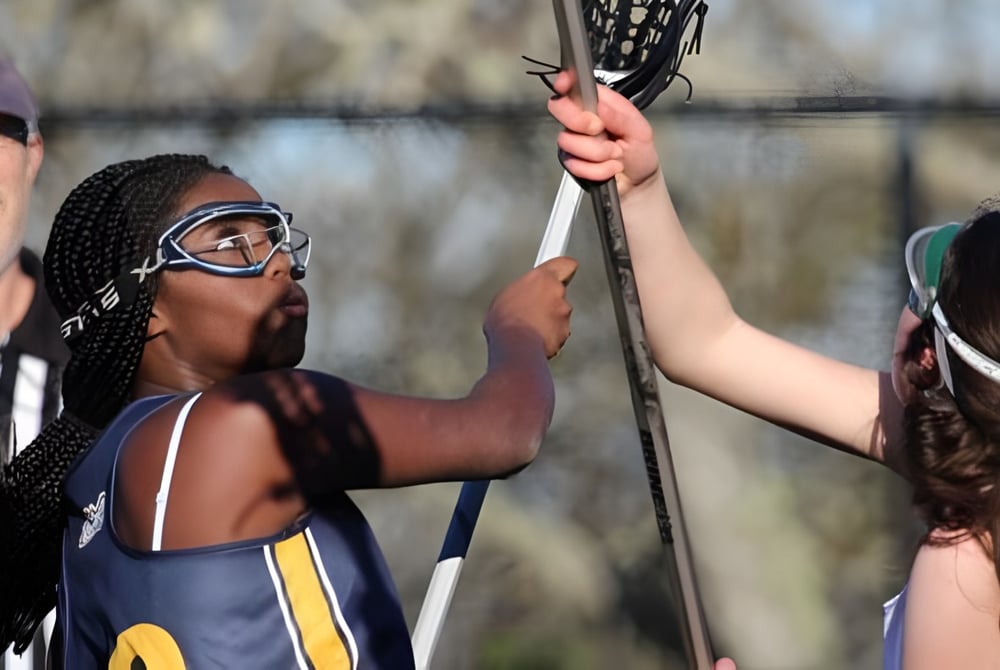 Zwei Schülerinnen der Annie Wright Schools spielen Lacrosse auf dem Spielfeld.