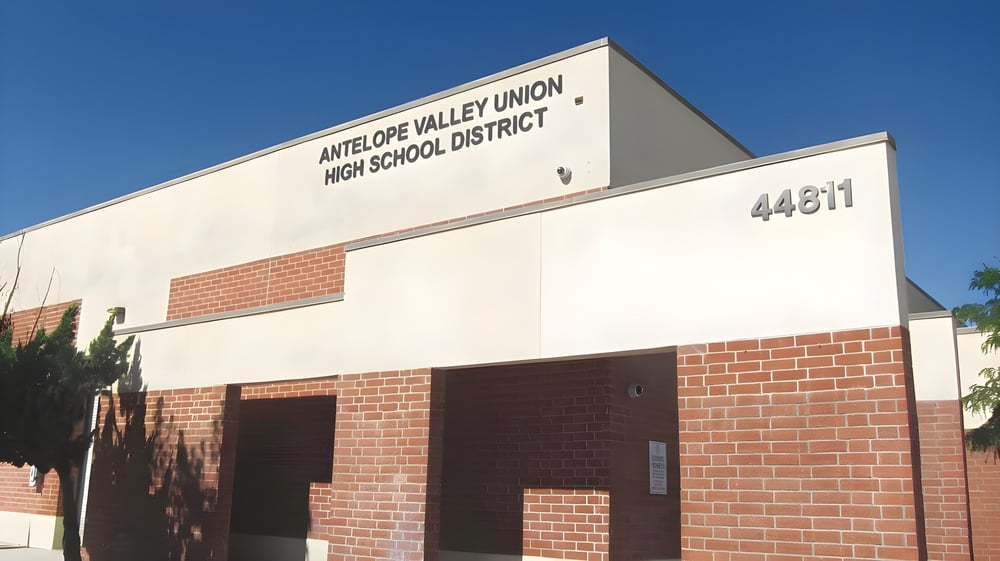 Das große Gebäude des Antelope Valley Union High School District aus Backstein und Beton vor einem klaren blauen Himmel.