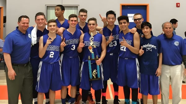 Eine Gruppe von Basketballschülerinnen und -schülern der Apple Valley Christian School in blauen Trikots posiert in einer Sporthalle.