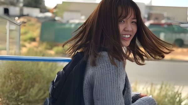Eine Schülerin der Apple Valley Christian School steht lächelnd auf einem Grasfeld mit Gebäuden im Hintergrund.