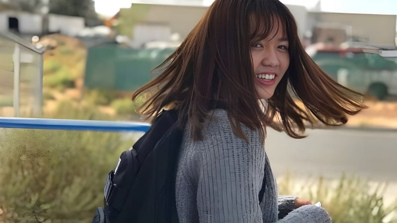 Eine Schülerin der Apple Valley Christian School steht lächelnd auf einem Grasfeld mit Gebäuden im Hintergrund.