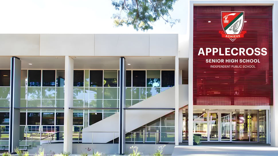 Das Gebäude der Applecross Senior High School mit einer großen roten Beschilderung ist von Bäumen und Grünflächen umgeben.