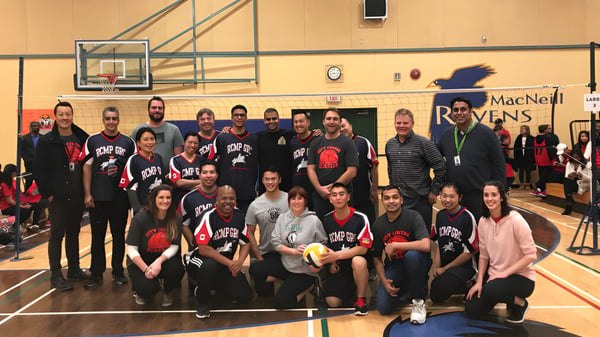 Eine Gruppe von Schülerinnen und Schülern der A.R. MacNeill Secondary School posiert in der Sporthalle mit Basketballkörben im Hintergrund.