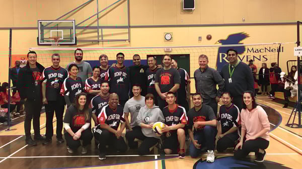 Eine Gruppe von Schülerinnen und Schülern der A.R. MacNeill Secondary School posiert in der Sporthalle mit Basketballkörben im Hintergrund.