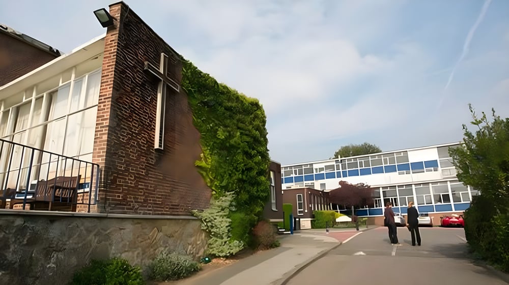 Das Backsteingebäude der Archbishop's School mit vertikalem Garten an der Fassade und modernem Umfeld ist zu sehen.