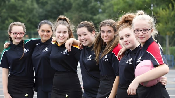 Eine Gruppe Schülerinnen der Archbishop's School steht lächelnd im Freien vor Bäumen und Grünflächen.