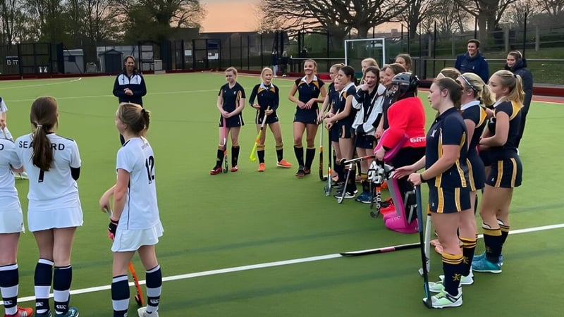 Eine Gruppe junger Sportlerinnen steht auf dem Sportplatz des Ardingly College mit Bäumen und Gebäuden im Hintergrund.