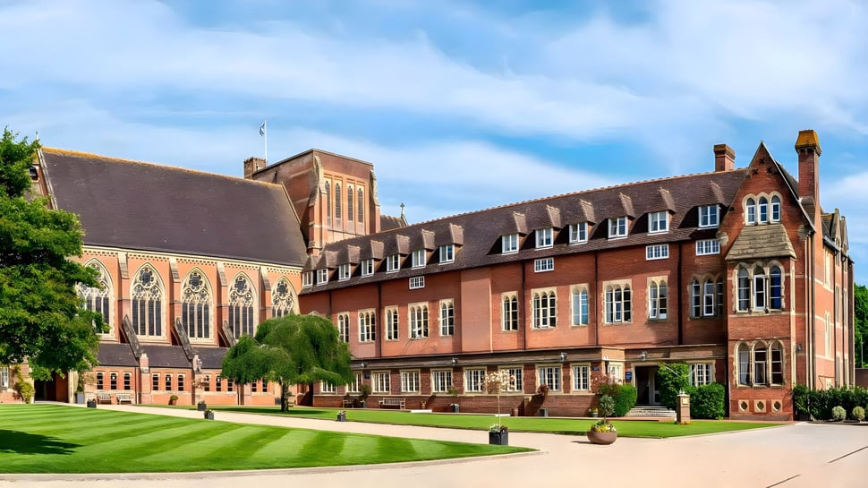 Das historische Backsteingebäude mit aufwändigen architektonischen Details auf dem Campus des Ardingly College ist von gepflegtem Rasen und grünen Bäumen umgeben.