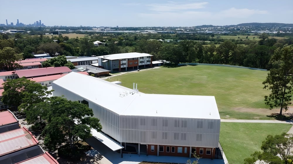 Ein großes Grasfeld mit Bäumen und einem modernen Gebäude auf dem Campus der Ardscoil Mhuire.